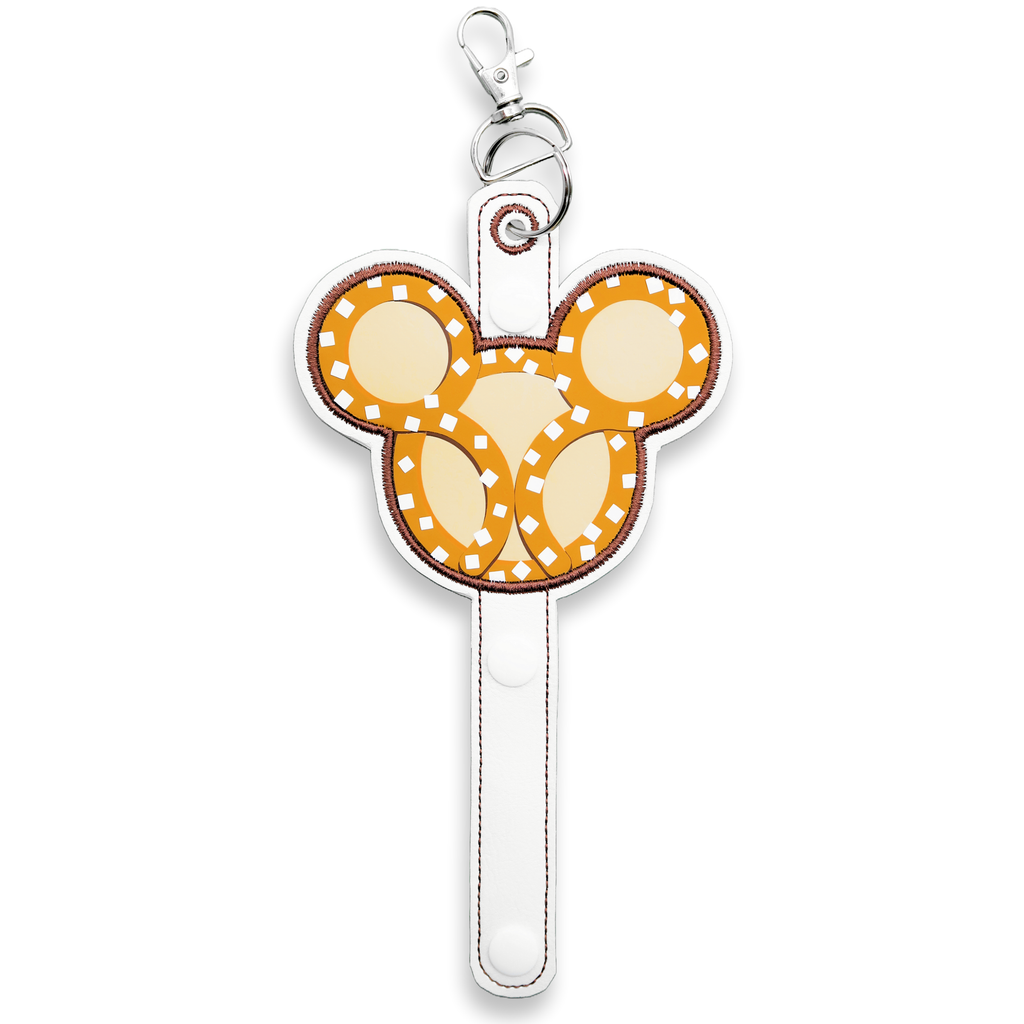 A holder with a Mickey Mouse pretzel-inspired design, predominantly white with gold details, attached to a snap closure and a lobster clip for carrying.