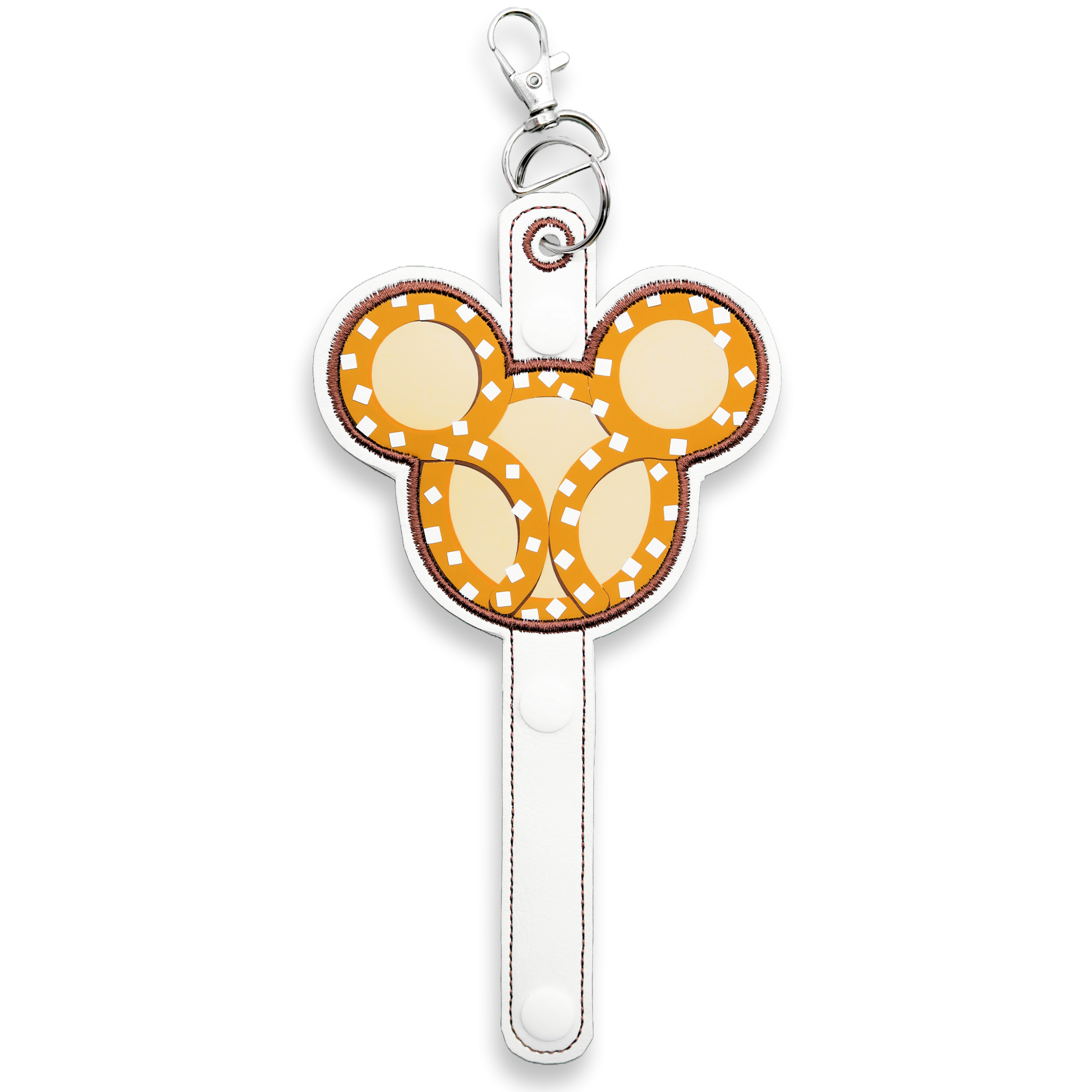 A holder with a Mickey Mouse pretzel-inspired design, predominantly white with gold details, attached to a snap closure and a lobster clip for carrying.